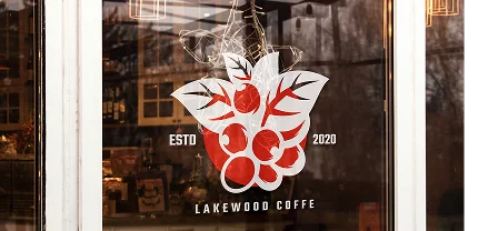 Window decal for "Lakewood Coffee" featuring a stylized cluster of red coffee cherries with white leaves. The text reads “ESTD 2020” on either side of the graphic, with the shop name displayed below.